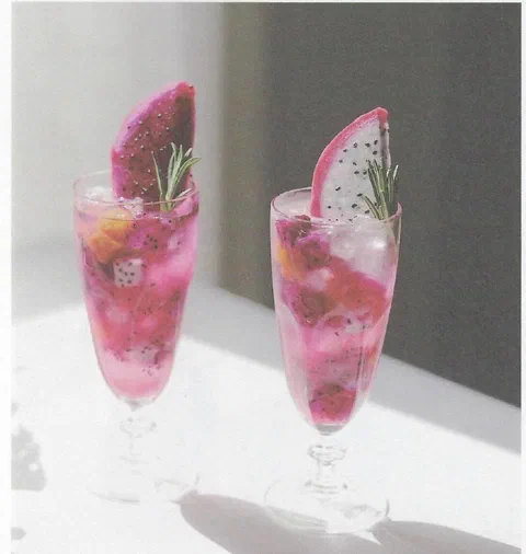 Ade tropical de invierno, de un rosa intenso, con una rodaja de pitahaya y romero de decoración