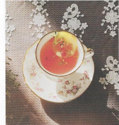 Té de toronja y miel, servido en una taza con rodaja de limón y hierbas