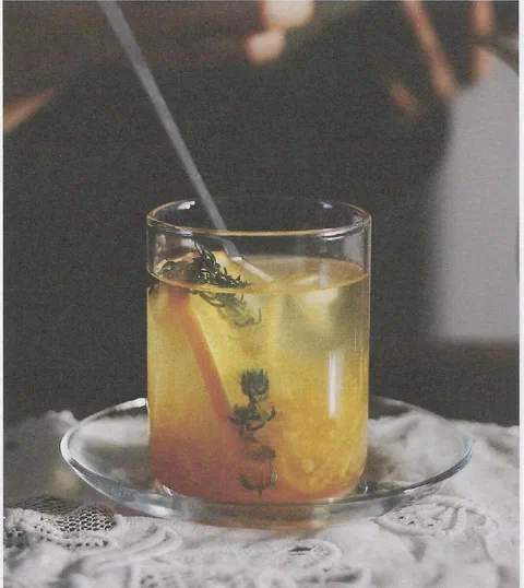 Té de toronja, mandarina y manzanilla, servido tibio en un vaso de vidrio