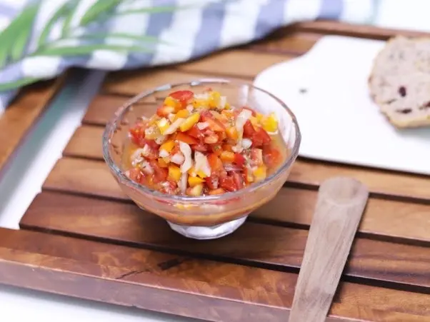 Aderezo tipo salsa con cebolla, ají limo y pimiento picados en un bowl de vidrio