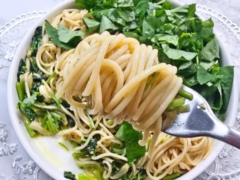 Espagueti aglio e olio con rúcula y berros, servido en un plato hondo