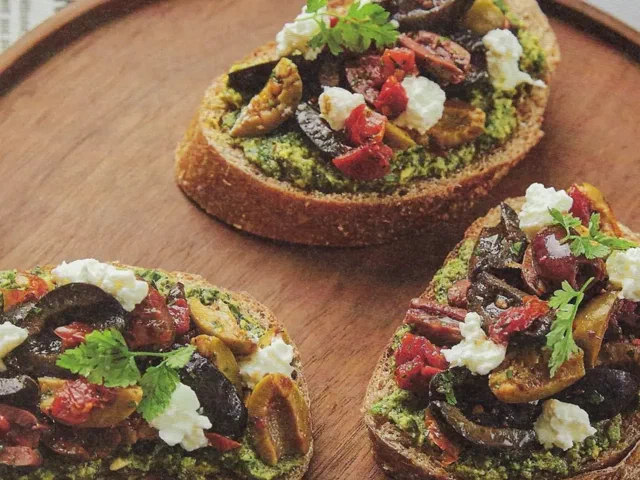 Untable de aceitunas variadas y tomate seco sobre pan con pesto de albahaca
