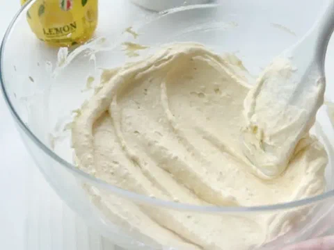 Crema de mantequilla de limón recién mezclada, con una botella de jugo de limón al fondo