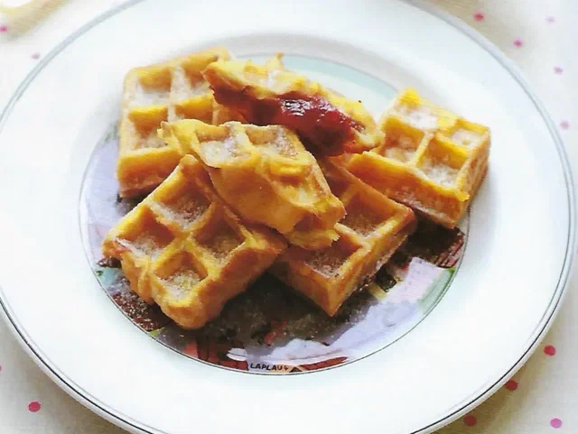Cuadrados de tostada francesa con sello de waffle, uno de ellos relleno de mermelada de fresa